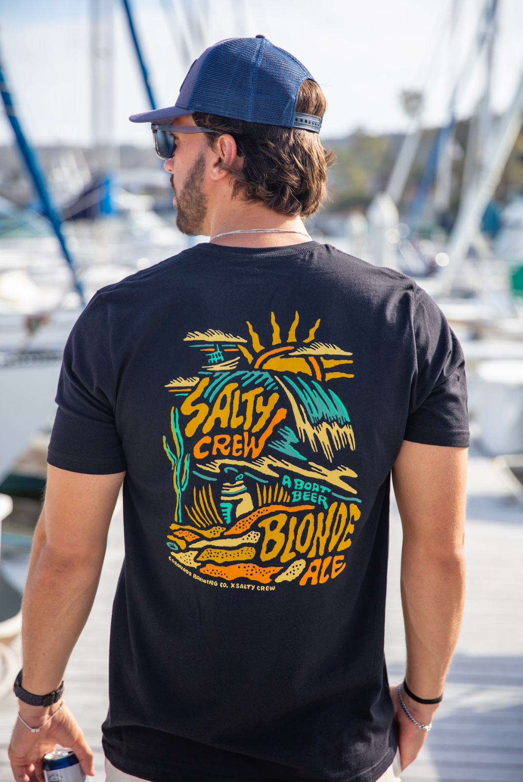 Man wearing a black t-shirt with 'Salty Crew' branding on a dock.