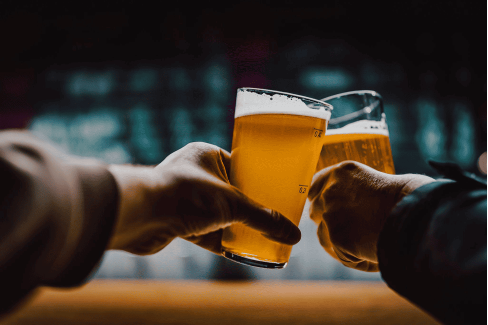 Two bar patrons clinking their beer glasses together