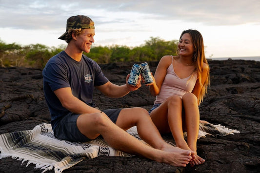 Couple toasting with Coronado Brewing Co. beers at sunset during a brewery festival picnic.